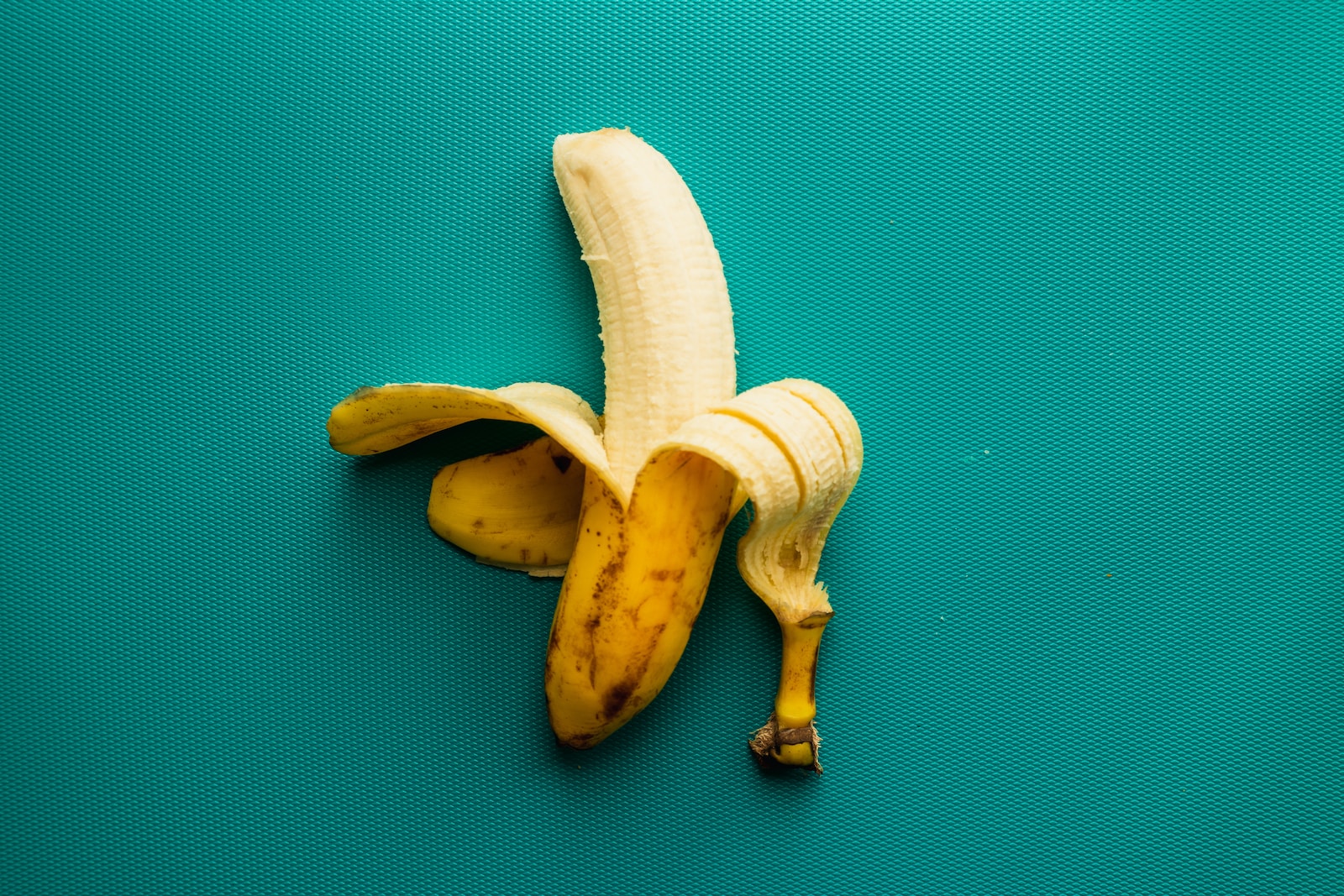 een gepelde banaan bovenop een blauw oppervlak